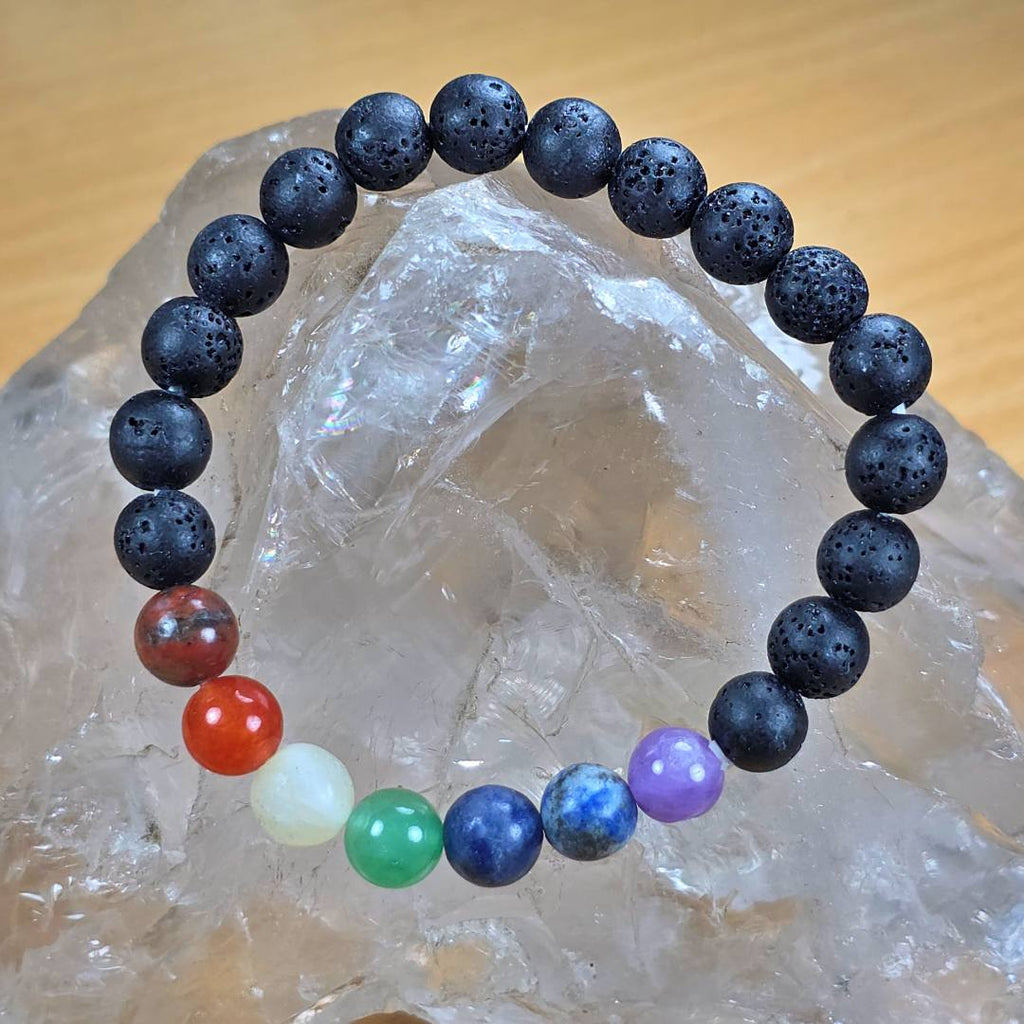 7 Chakra lava stone beaded bracelet for men and women displayed on natural crystal rock surface
