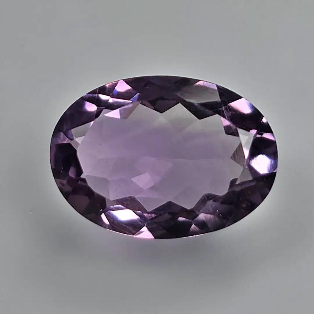 Faceted purple amethyst gemstone on a grey background