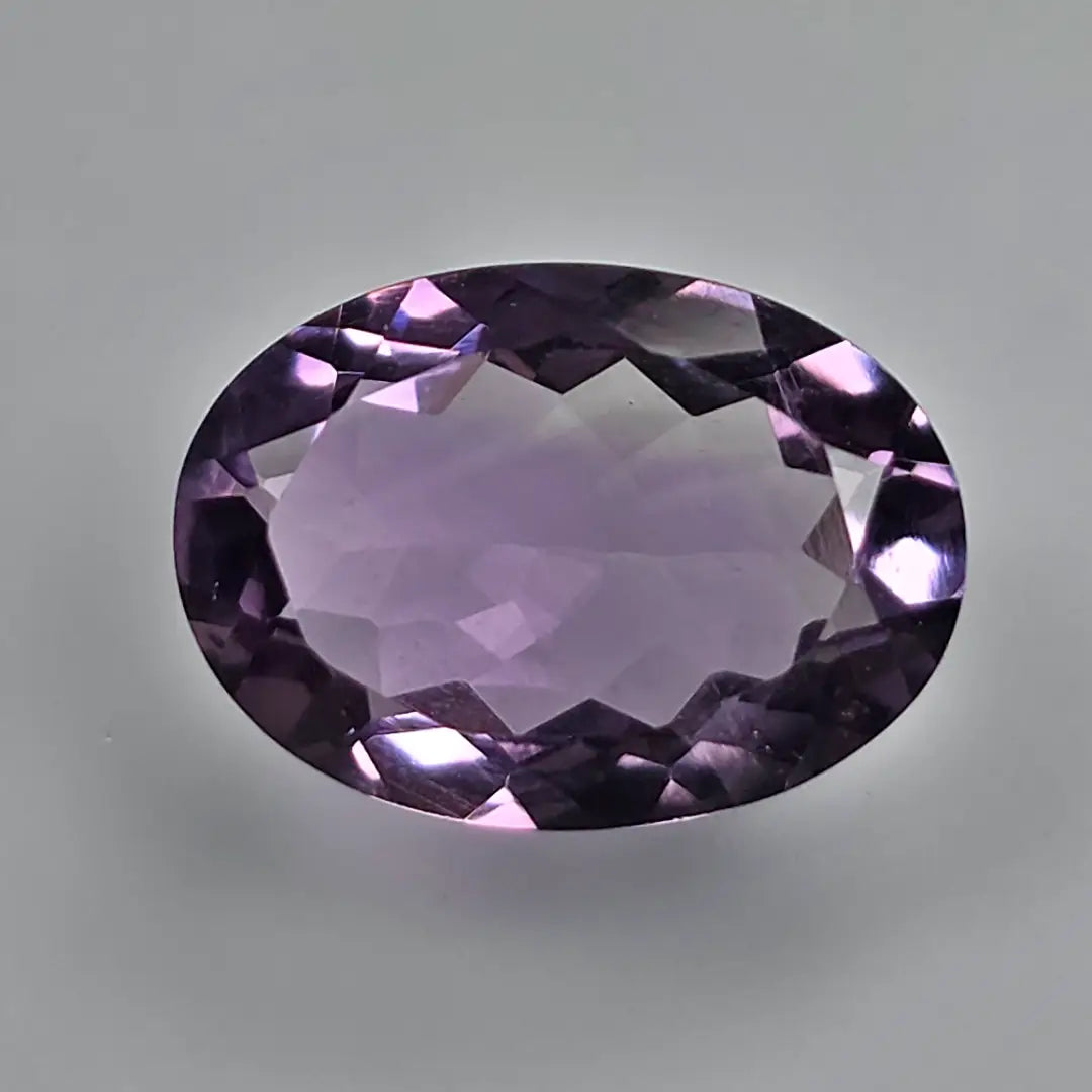 Faceted purple amethyst gemstone on a grey background
