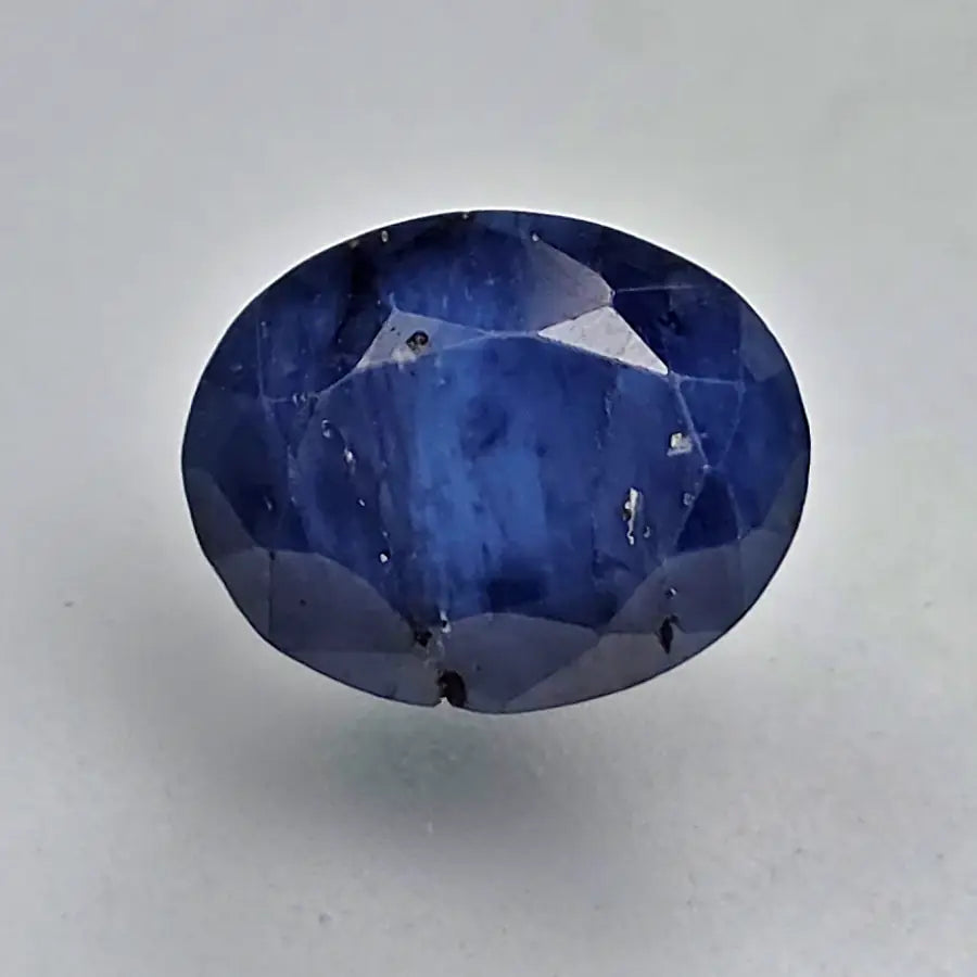Faceted blue sapphire gemstone on a light gray background online India