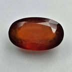 Faceted red-orange gemstone on a light gray background online India
