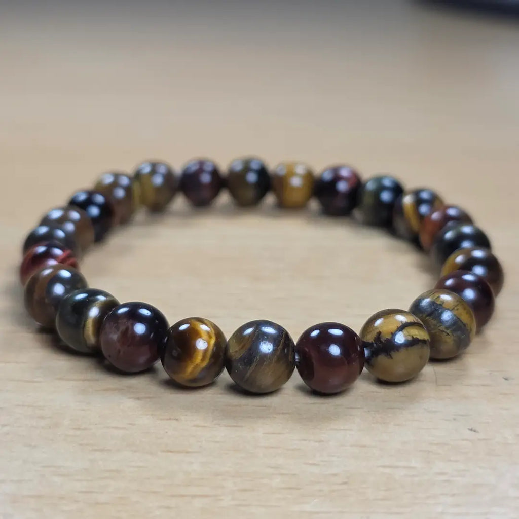 Tiger eye beaded bracelet with brown and black stones on a wooden surface