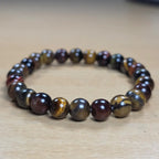 Tiger eye beaded bracelet with brown and black stones on a wooden surface