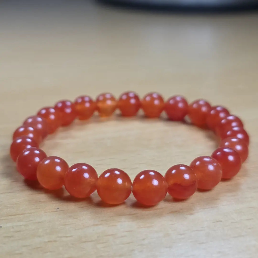 Orange beaded carnelian bracelet on a wooden surface