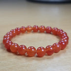 Orange beaded carnelian bracelet on a wooden surface
