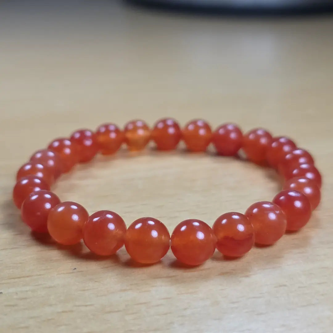 Orange beaded carnelian bracelet on a wooden surface