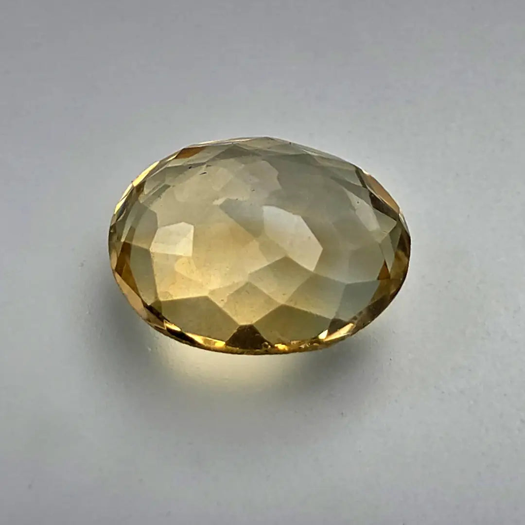 Faceted yellow citrine gemstone on a grey background