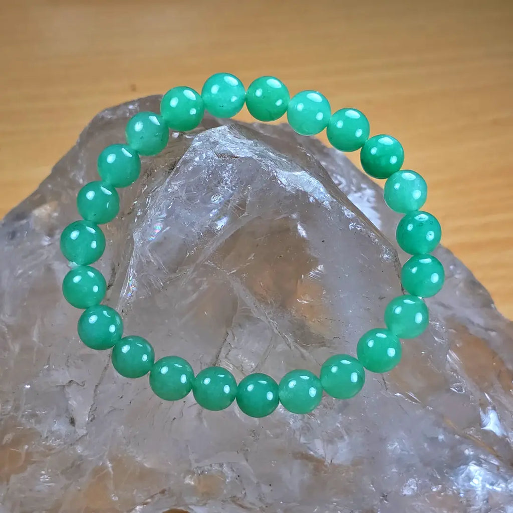 Green aventurine beaded bracelet on a crystal with a wooden background