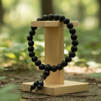 Black beaded karungali bracelet on a wooden stand with a natural outdoor background