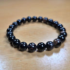 Natural black beaded tourmaline bracelet on a wooden surface
