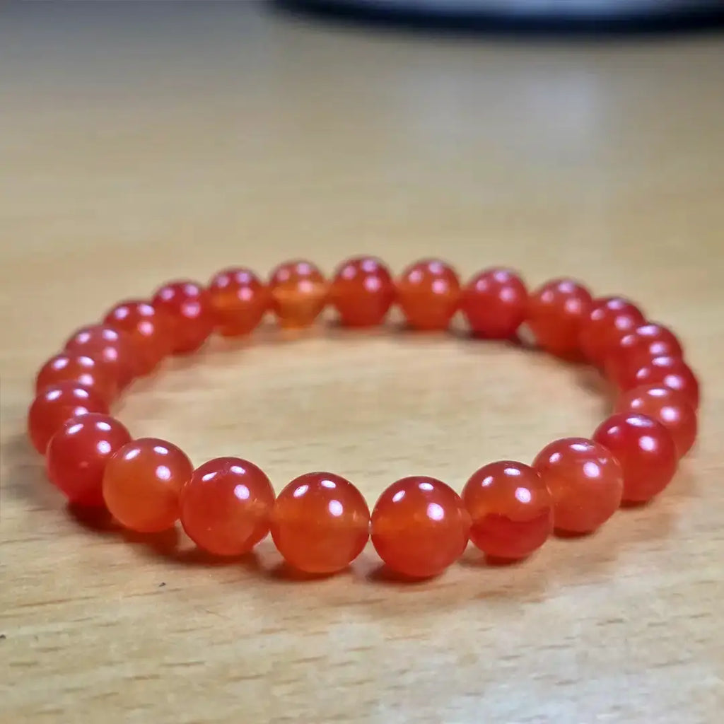 Red beaded carnelian bracelet on a wooden surface