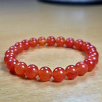 Red beaded carnelian bracelet on a wooden surface