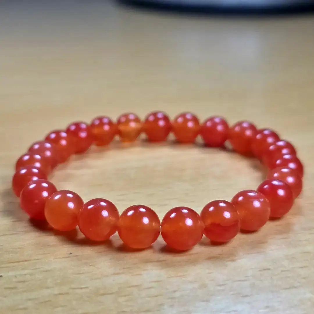 Red beaded carnelian bracelet on a wooden surface
