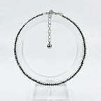 Necklace with black beads on a clear stand against a white background