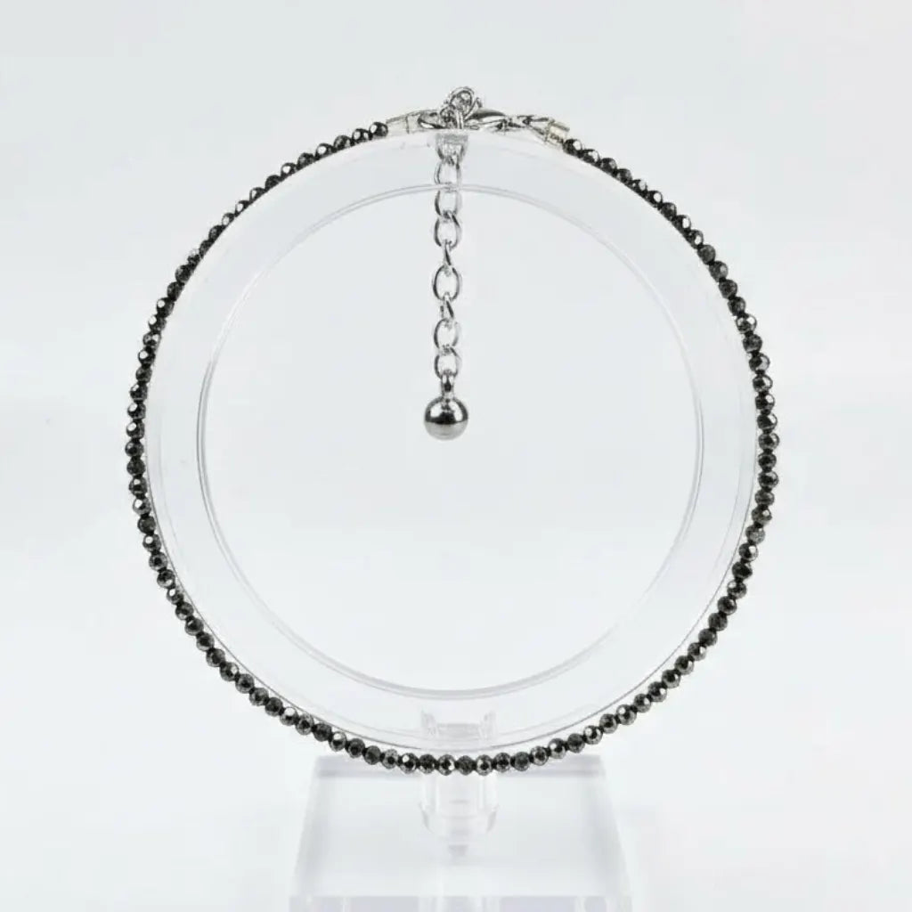 Necklace with black beads on a clear stand against a white background