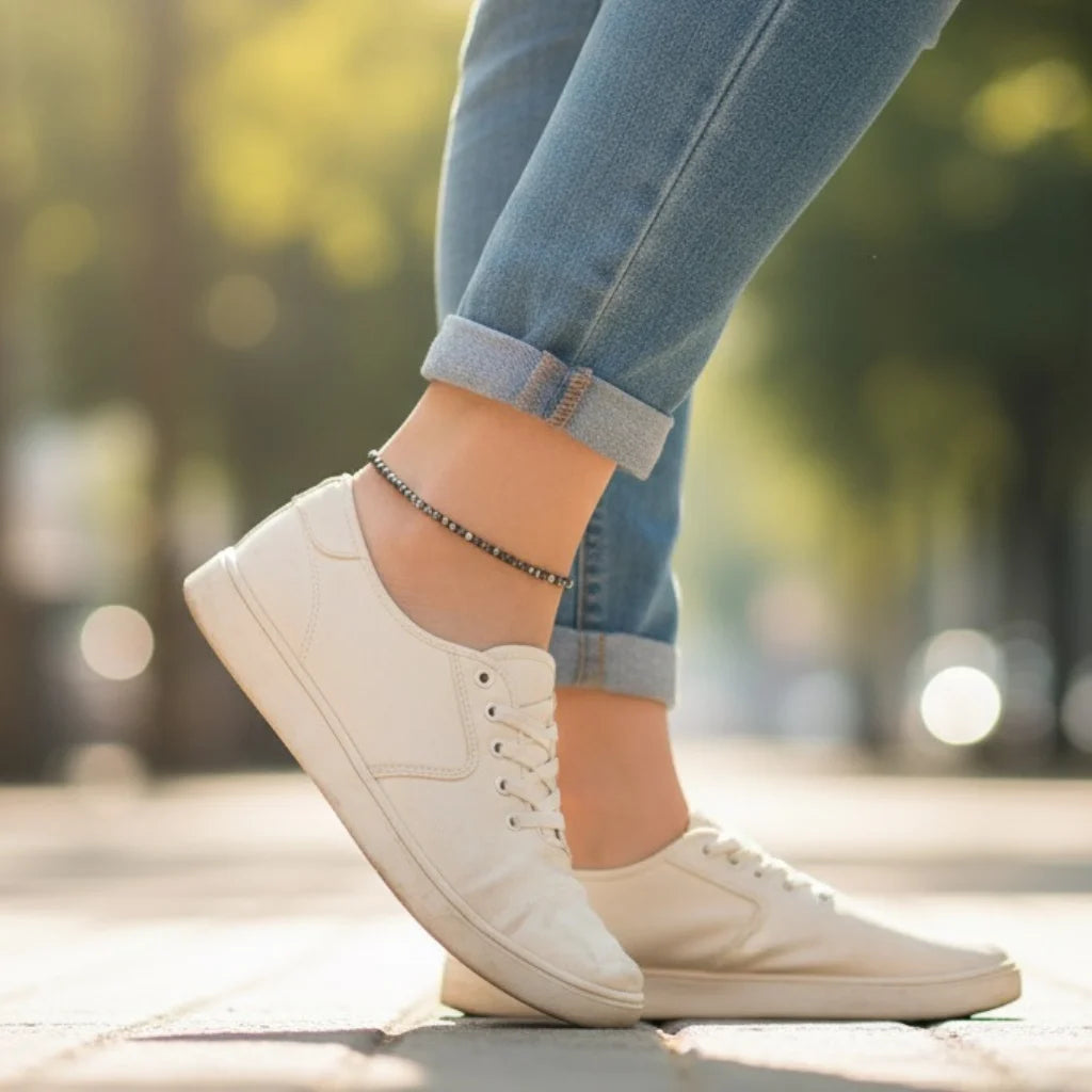 White sneakers worn with rolled-up jeans on a blurred outdoor background