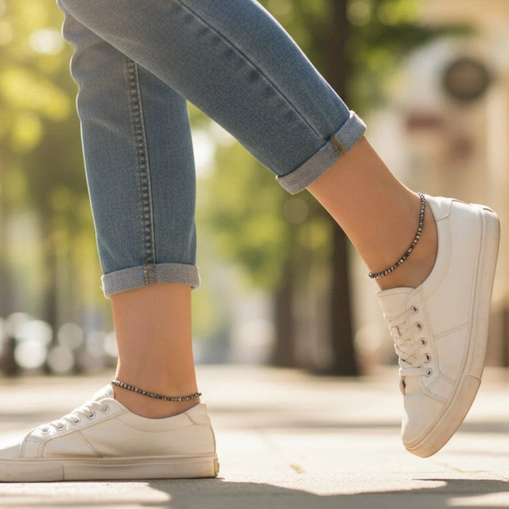 White sneakers worn with rolled-up jeans on a blurred outdoor background