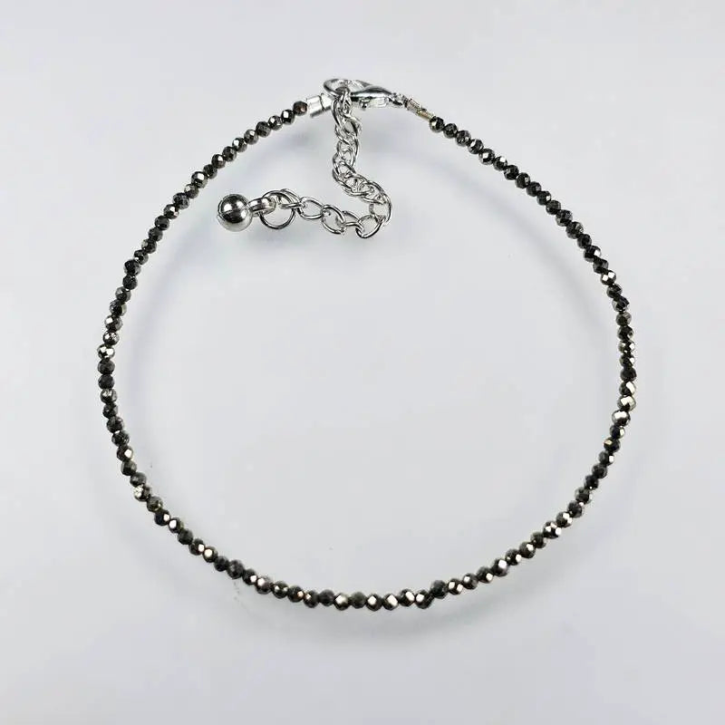 pyrite anklet with black beads on a light grey background