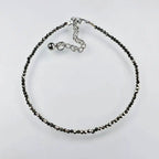 pyrite anklet with black beads on a light grey background