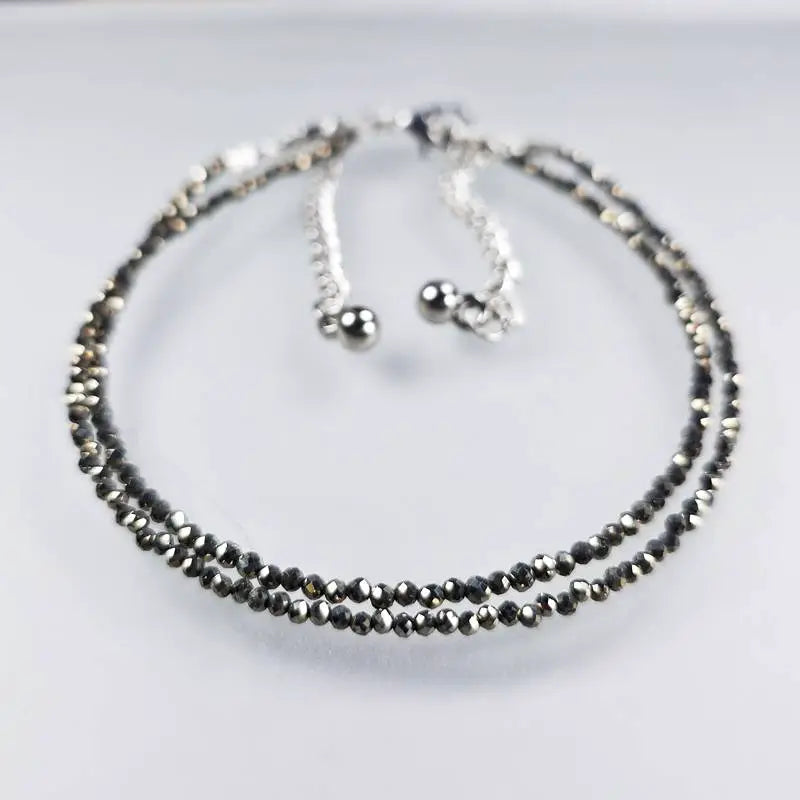 Set of pyrite stone anklet on a light grey background