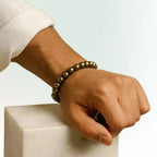 Hand wearing a beaded bracelet on a light background