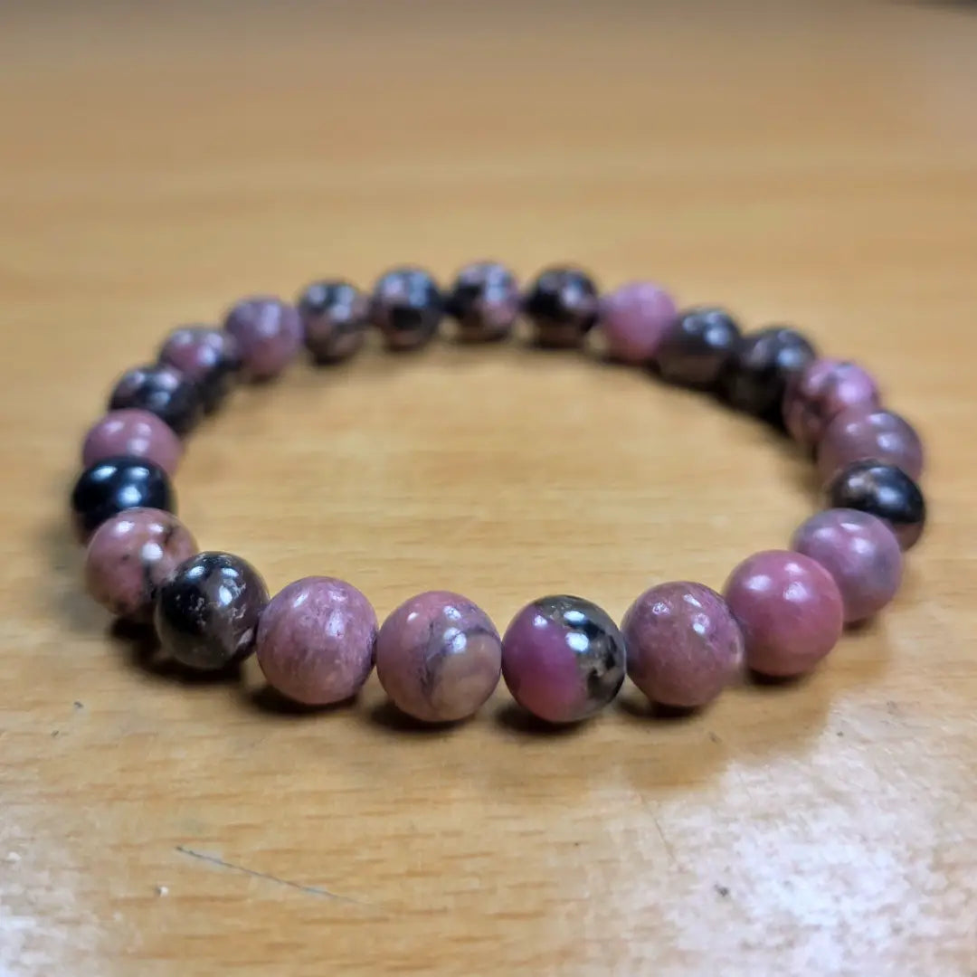 Beaded rhodonite bracelet with pink and black beads on a wooden surface