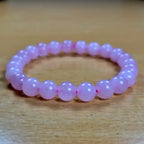 Pink beaded rose quartz women bracelet on a wooden surface