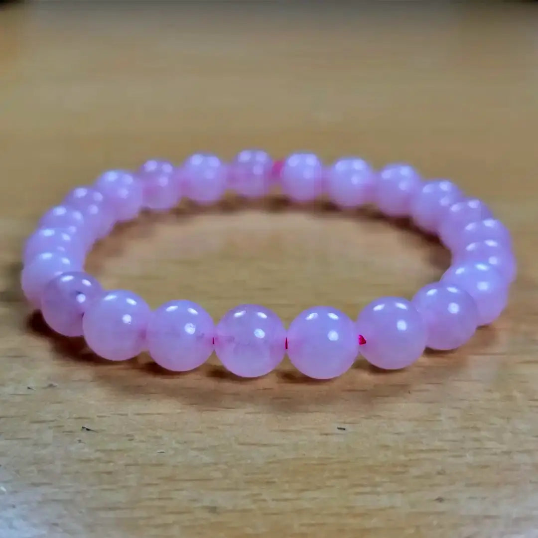 Pink beaded rose quartz women bracelet on a wooden surface