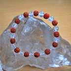 rudraksha crystal bracelet with red and clear beads on a crystal rock