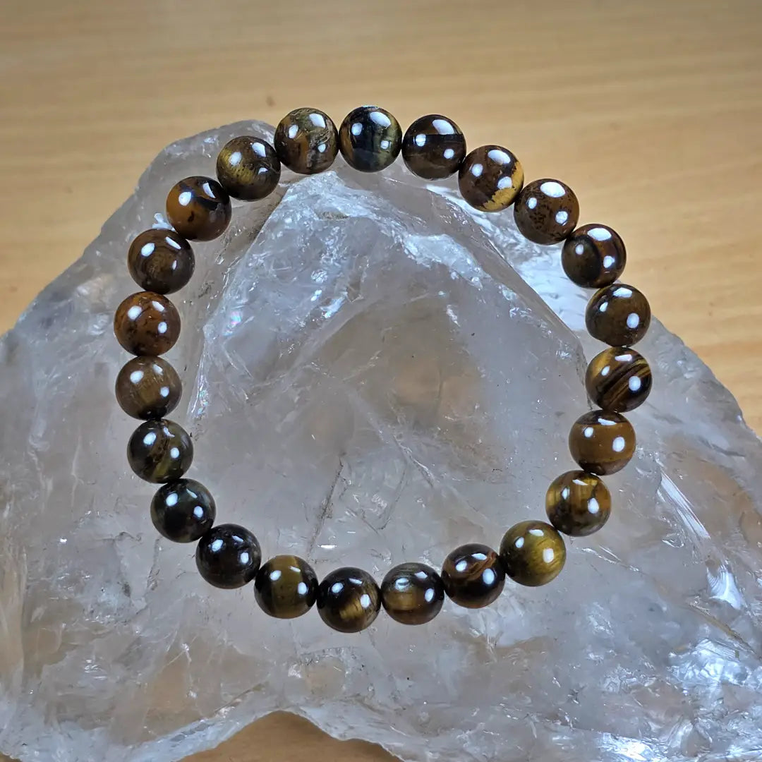 Brown beaded tiger eye bracelet on a clear crystal with a wooden background