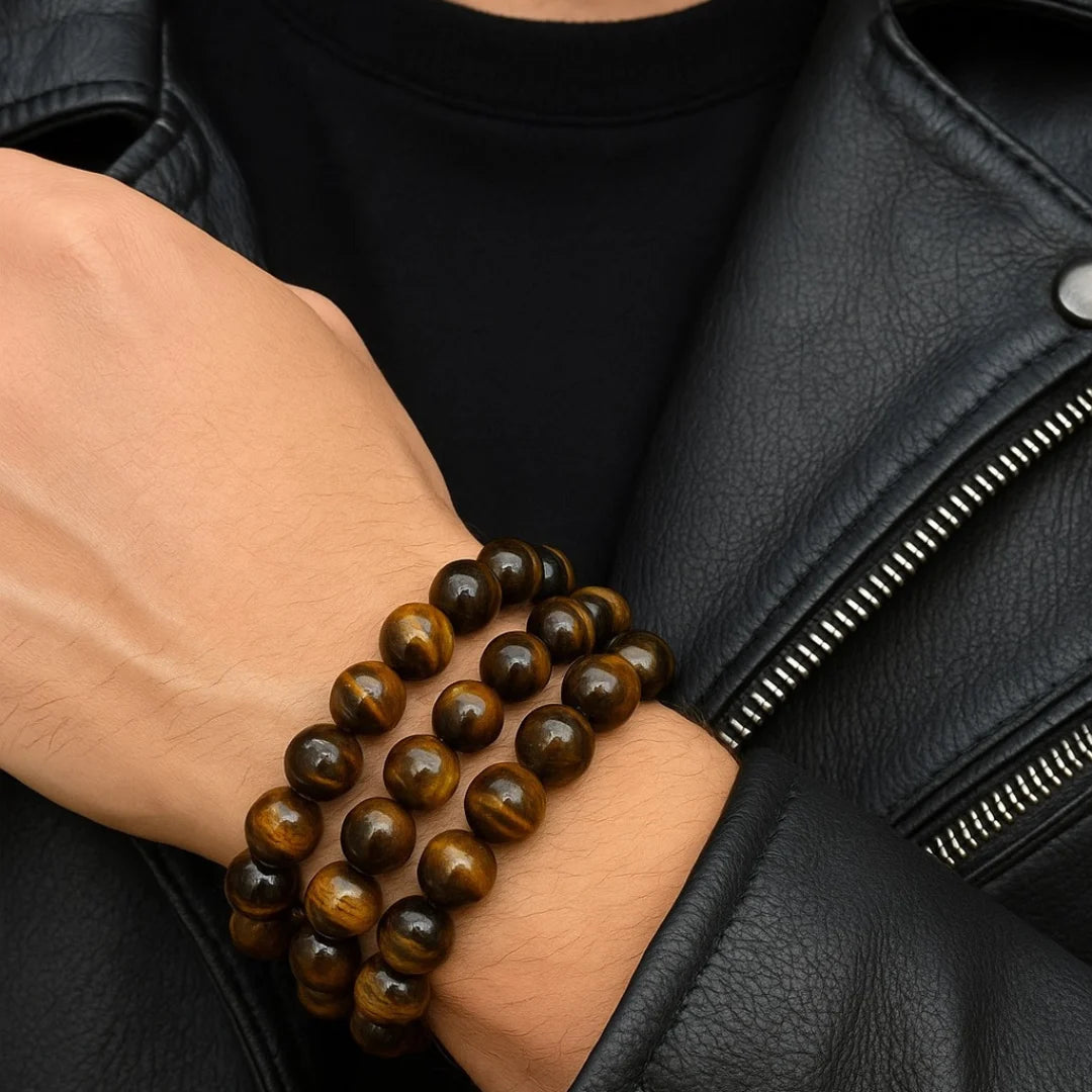 Person wearing a black leather jacket with a focus on a tiger eye bracelet on a wrist.