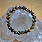 Brown beaded tiger eye bracelet on a clear crystal with a wooden background