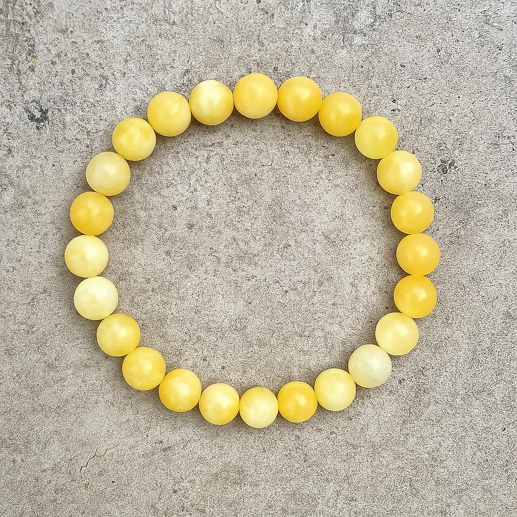 Round yellow calcite bracelet resting on a textured crystal surface