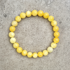 Round yellow calcite bracelet resting on a textured crystal surface
